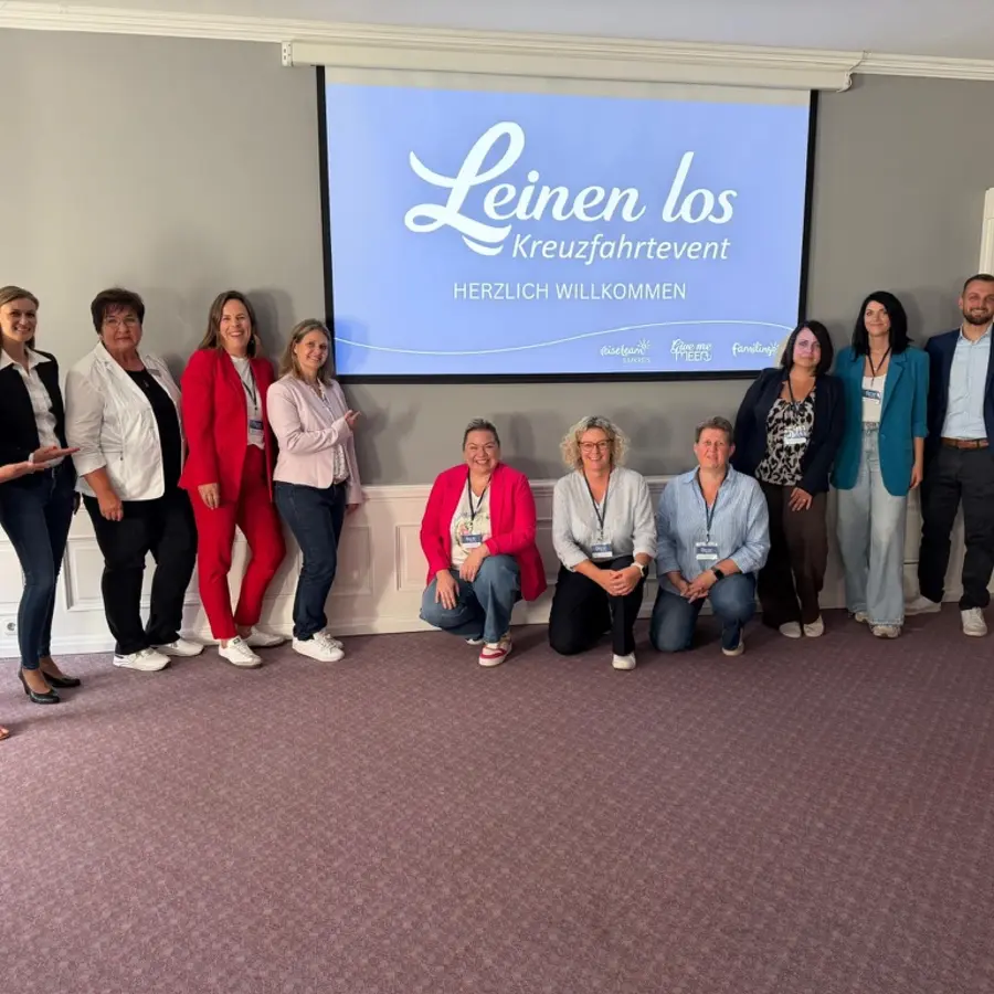 Unser Team steht vor der Leinwand mit dem Leinen-los-Kreuzfahrtevent-Logo