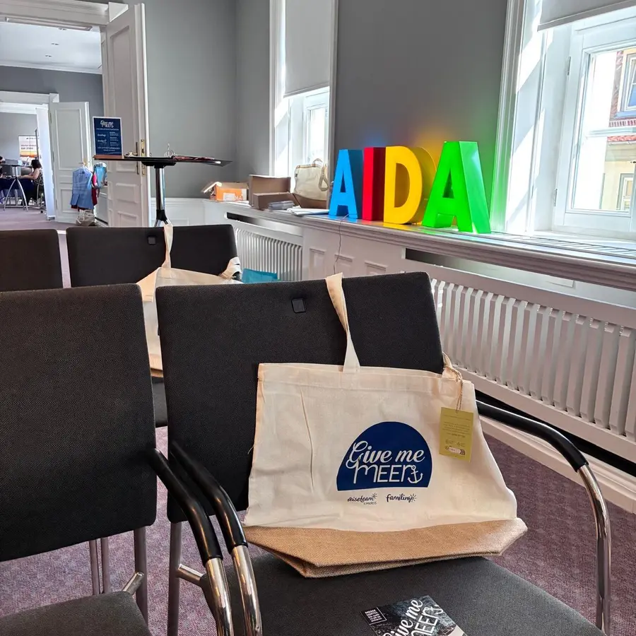 Stuhlreihen mit Give-me-Meer-Taschen auf jedem Platz, im Hintergrund die AIDA-Buchstaben