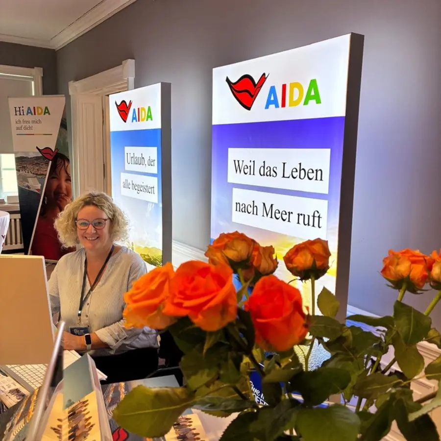 Kollegin vor AIDA Roll-ups mit frischen Rosen im Vordergrund