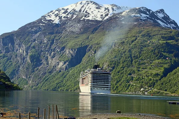 Kreuzfahrtschiff im Geirangerfjord vor schneebedeckten Bergen